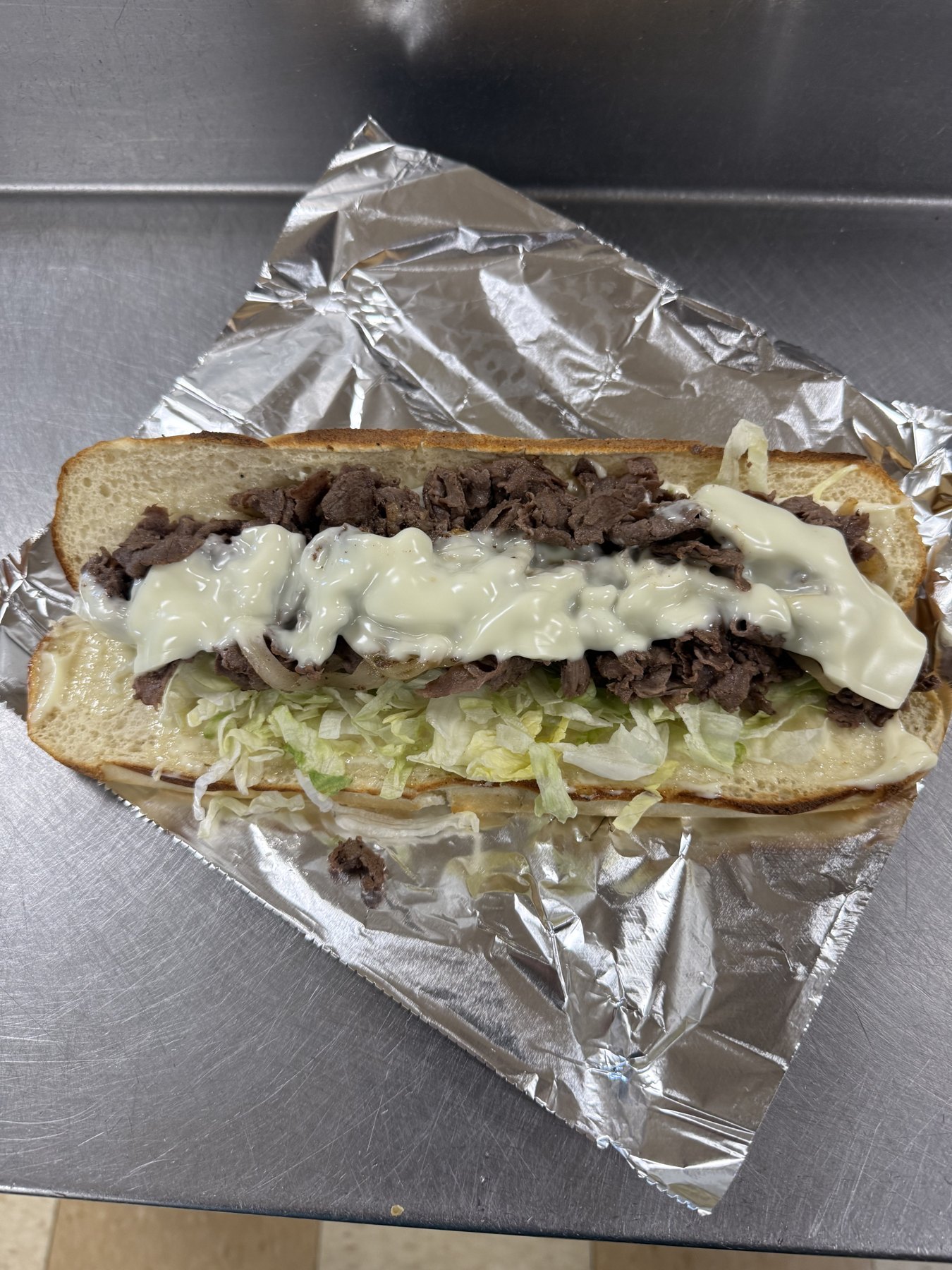 A hot sub with steak, lettuce and melted cheese from Fred's